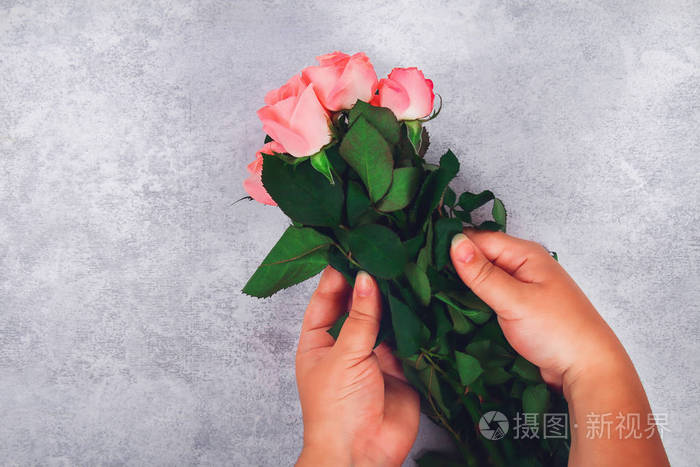一束粉红色的玫瑰在一个女孩的手在一个光的背景