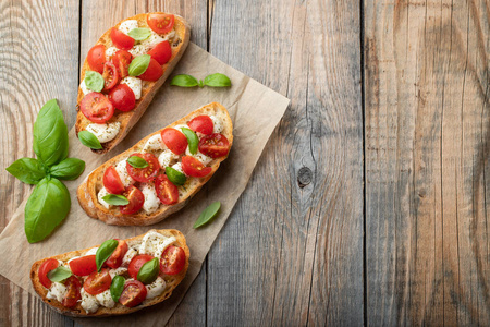 Bruschetta 有西红柿, 芝士干酪和罗勒在一个古老的乡村餐桌上。传统的意大利开胃菜或小吃, 开胃菜来。具有复制空间的顶部