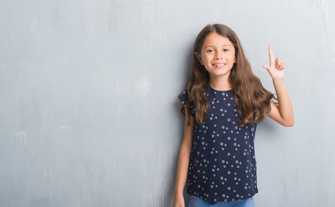 年轻的西班牙裔孩子在垃圾灰色墙壁显示和指向的手指第二, 而微笑着自信和快乐