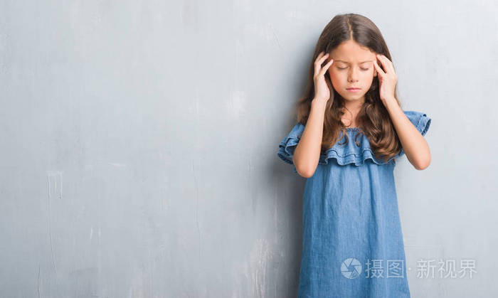 年轻的西班牙裔孩子在灰墙上, 手放在头上, 因为压力而头痛.患偏头痛