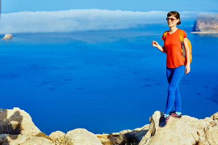 旅行者女人在悬崖上，也海滩，克里特岛