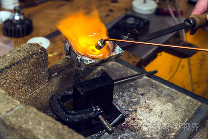 黄铜金属与火炬火焰熔化在一个坩埚在工作地点的金匠为执行工艺品金属