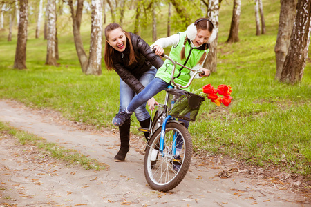 妈妈抱着女儿快乐妈妈教他的女儿在公园里骑自行车.