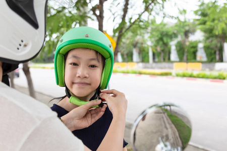 安全骑马概念。母亲试图戴自行车头盔给他的女儿, 摩托车司机戴安全帽前骑车作为事故预防
