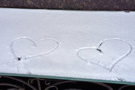 在雪地上涂上新鲜的雪花两颗心作为爱的象征, 在冬天的街道上的门的遮阳