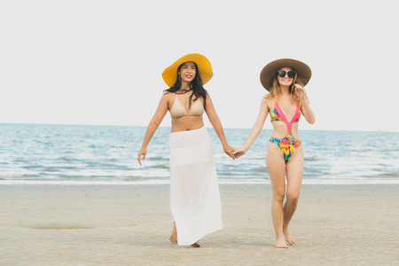 快乐的比基尼妇女在夏季的热带沙滩上一起日光浴。旅游生活方式