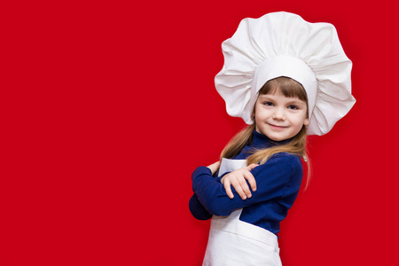 美丽的小女孩的肖像, 以厨师的形式孤立的红色。小厨师烹调过程概念