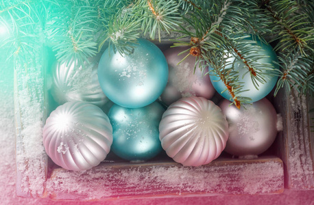古老的木制古董盒与美丽的粉红色和蓝色的圣诞球在背景与绿色冷杉分支和明亮的灯光