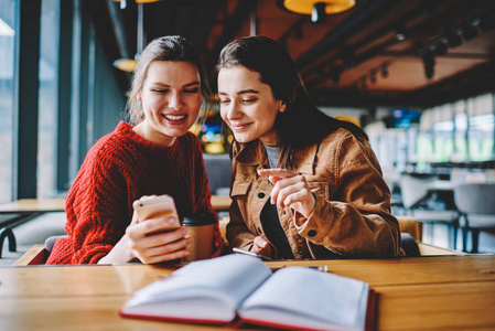 快乐的白种时髦女孩阅读来自朋友的短信使用电话设备进行通信, 积极的妇女在大学校园里用技术消磨空闲时间学习