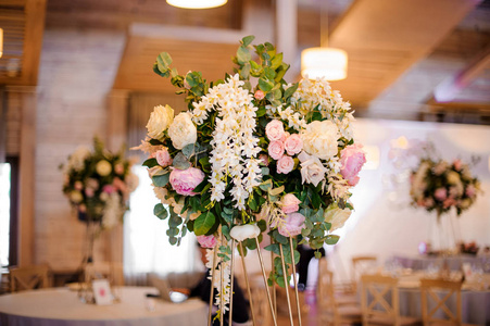 婚礼装饰花束的招标粉红色的牡丹和玫瑰与绿色的叶子下天花板上的大厅模糊背景