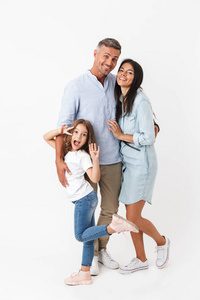 一个幸福的家庭的肖像父亲, 母亲, 小女儿抱着孤立的灰色背景