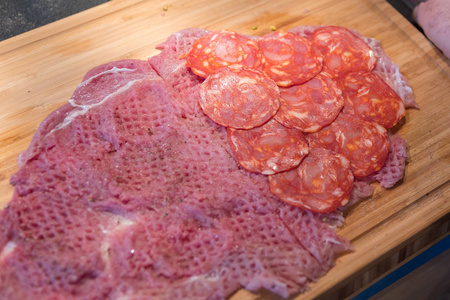 香肠和培根在木制切板上制备美味自制猪肉里脊卷, 特写