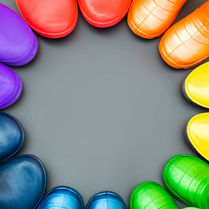 彩色橡胶靴的所有颜色的彩虹红色, 橙色, 黄色, 绿色, 蓝色, 青色和紫色的立场在灰色的表面在一个圆圈。顶部视图, 文本空间