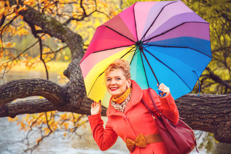 秋天公园里带着雨伞的快乐金发女郎