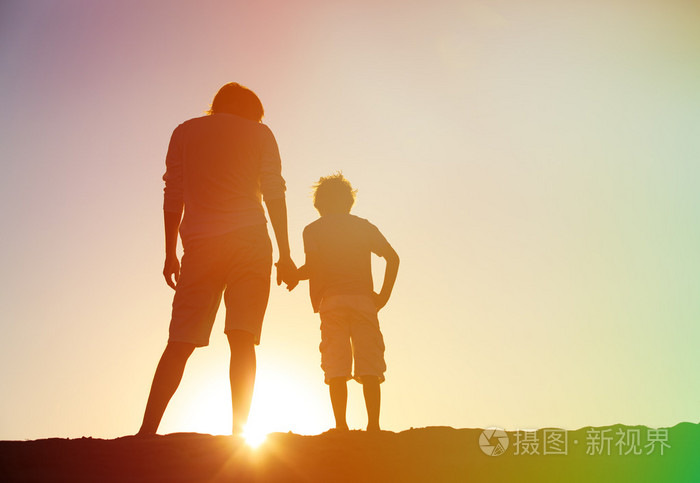 父子俩手牵着手在日落时分
