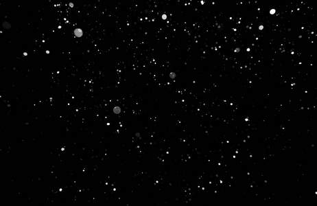 暴风雪的纹理。在黑色背景上的散景灯拍摄的飞片雪花在空中