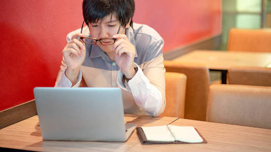 年轻的亚裔男子戴着眼镜, 而在大学里使用笔记本电脑。男大学生做研究和自学。教育和技术 comcepts
