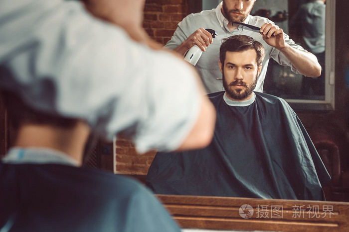 年轻英俊的理发师在理发店理发的有魅力的男人