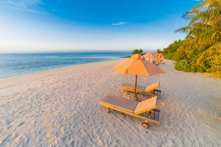 日落海滩场面, 柔和的阳光, 蓝色海, 海滩椅子雨伞。异国风情的热带景观。令人惊叹的热带景观