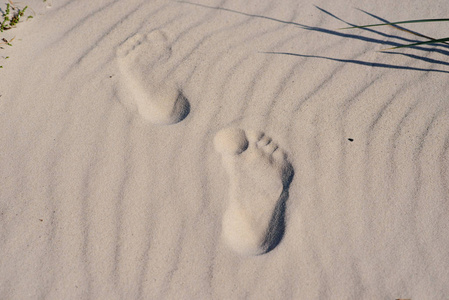 脚印或两个人脚在沙滩上的痕迹。度假理念