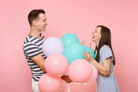 年轻快乐的微笑情侣的肖像在爱。穿着蓝色衣服的女人和男人在粉红色的背景上庆祝生日派对, 彩色热气球。人的真诚情感理念