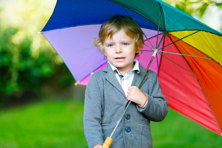 小可爱宝宝男孩与花伞和靴子，户外