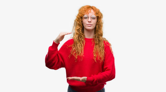 身穿红色毛衣手势的年轻红发女子手上显示大尺寸标志, 测量符号。微笑着看着相机。测量概念