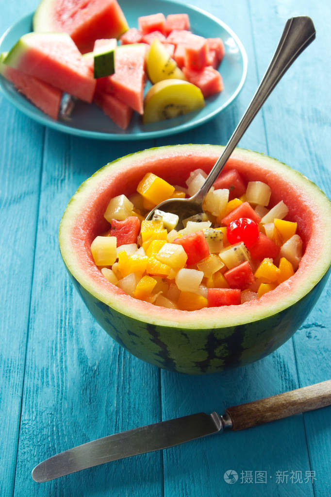 乡土餐桌上用勺子雕刻的西瓜碗水果沙拉