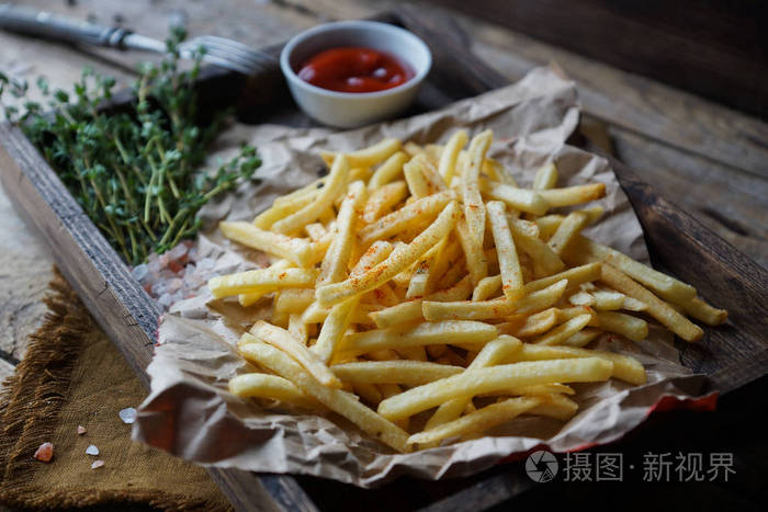 在乡间木桌上用百里香和番茄酱煎土豆。快餐套装, 饮食观念不健康。法式薯条配番茄酱, 选择性对焦