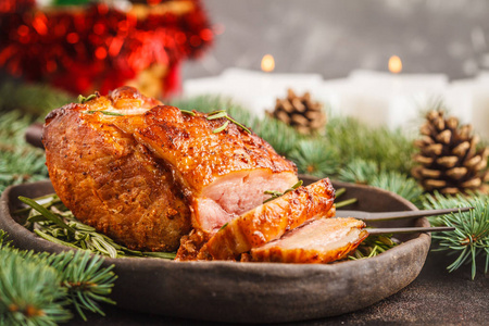 烤圣诞猪肉 火腿 配以迷迭香。圣诞餐桌, 节日背景概念。到处都是云杉的树枝。前视图