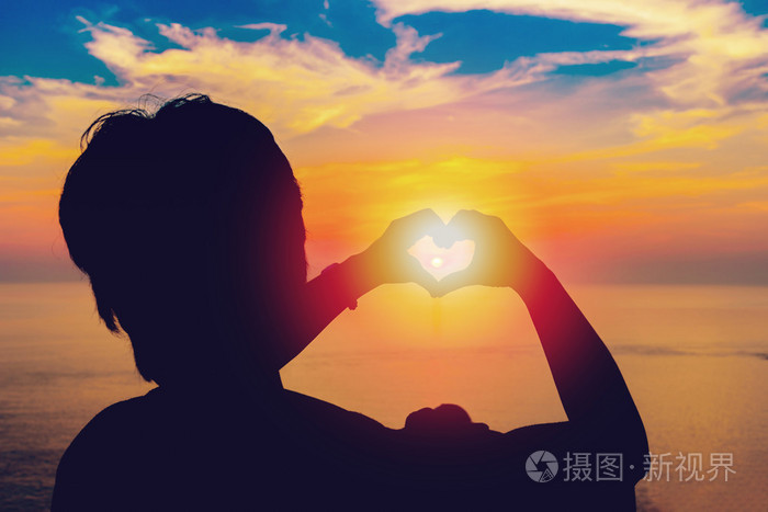夕阳中的中间和海背景心形剪影手