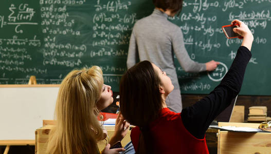 学生通过考试兴高采烈的女孩在教室里看笔记本电脑。概念教育回到学校在绿色背景。学生使他的学习优先