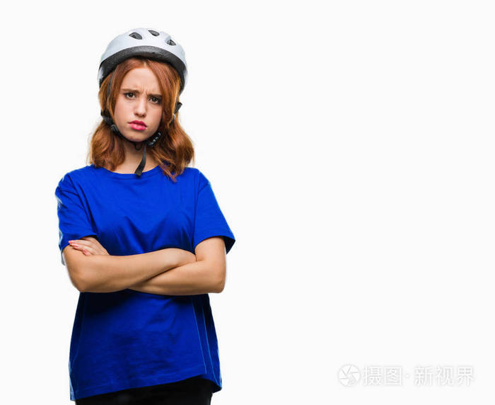 年轻美丽的女人穿着自行车头盔在孤立的背景怀疑和紧张, 不赞成的表情与交叉的武器。消极的人