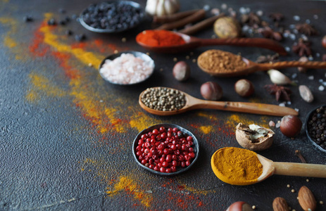 各种印度香料在木勺, 香草和坚果在黑暗的石桌上。色彩缤纷的意大利香料, 顶级景观。有机食品, 健康生活方式, 文字空间, 横幅