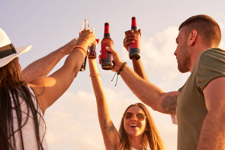 为啤酒欢呼快乐的搞笑年轻朋友举起啤酒瓶举手, 一边为完美的假期欢呼