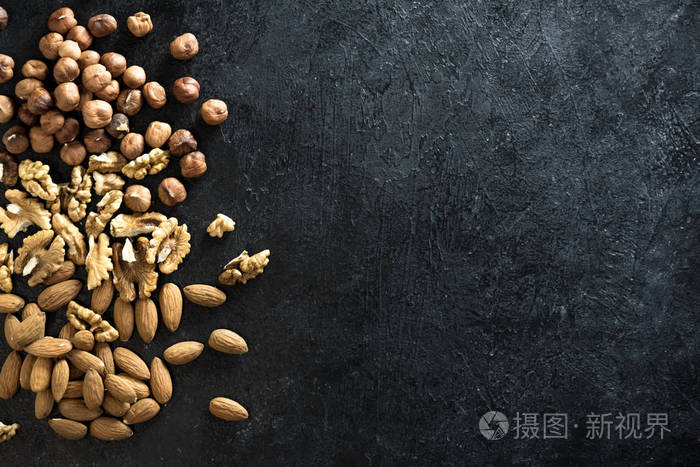各种坚果 (核桃, 榛子, 杏仁) 黑色石材背景, 顶部视图, 复制空间