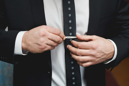 领带夹放领带夹的黑色西装的男人照片