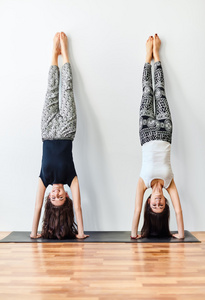 两个年轻妇女做瑜伽倒立构成
