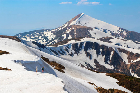风景与草甸, 高山和山顶被雪覆盖。短裤和照相机的人都住在鸿沟的边缘。喀尔巴阡山乌克兰欧洲的游客的地方休息。美好的春天晴朗的天
