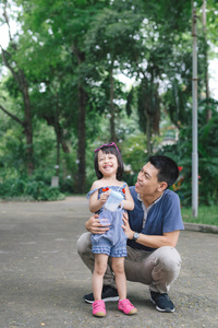 可爱的小女孩走在绿色公园与父亲