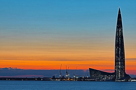 Lahta 中心摩天大楼建筑在靠近彼得斯堡市的海岸上, 在夕阳的照耀下, 在不远河的河口。美丽的橙色和红色的城市景观