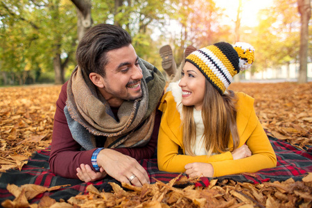 幸福的情侣，在公园的秋天对着镜头微笑