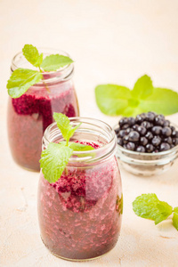 蓝莓奶昔, 用新鲜的绿色薄荷叶和原始成熟的浆果点缀在黄色柔和的背景上夏季混合维生素鸡尾酒与复制空间的透明罐子