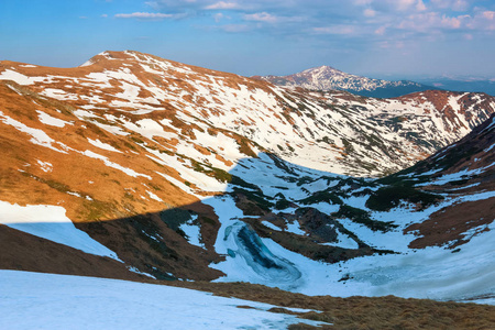 湖的风景在霜冻在高山和领域覆盖了雪。天空与云彩。阳光明媚的春天。生态旅游休息