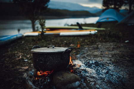 野营和烹饪在野外条件下, 在篝火上煮沸的锅在早晨野餐。当你去野外或户外活动时, 用木柴在柴火炉上做饭, 露营帐篷