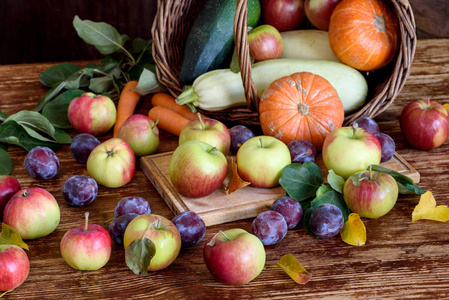 桌子上有苹果和李子。蔬菜在篮子里。秋收。乡村风格