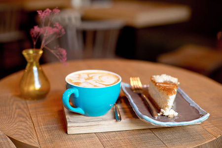 木托盘与咖啡在蓝色杯子和烘烤的果子馅饼在现代咖啡馆内部