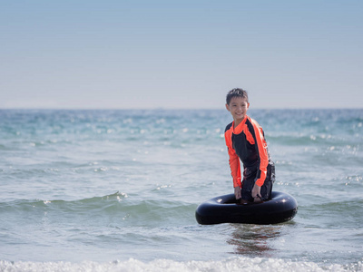 小亚洲男孩在海滩上玩波浪, 救生圈