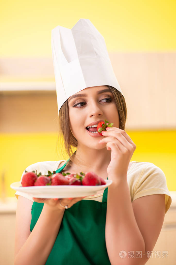 年轻女厨师吃草莓