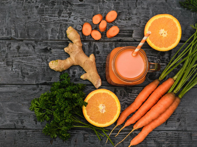 新鲜的胡萝卜冰沙, 一束胡萝卜, 橙色和生姜根在一个质朴的桌子上。从顶部的视图。健康饮食的概念。平躺